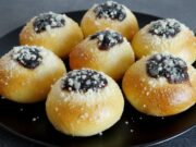 Hausgemachte weiche Kolatschen mit Powidl, Quark und Rum Hausgemachte weiche Kolatschen mit Powidl, Quark und Streuseln auf einem schwarzen Teller.