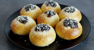 Hausgemachte weiche Kolatschen mit Powidl, Quark und Rum Hausgemachte weiche Kolatschen mit Powidl, Quark und Streuseln auf einem schwarzen Teller.