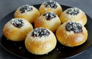 Hausgemachte weiche Kolatschen mit Powidl, Quark und Rum Hausgemachte weiche Kolatschen mit Powidl, Quark und Streuseln auf einem schwarzen Teller.
