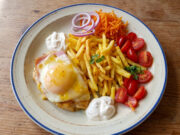 Hähnchenbrust mit Schinken, Käse und Pfirsich: Retro-Mittagessen mit Pommes Hähnchenbrust mit Schinken, Käse und Pfirsich auf einem Teller mit Pommes