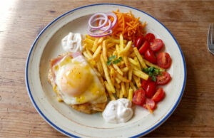 Hähnchenbrust mit Schinken, Käse und Pfirsich: Retro-Mittagessen mit Pommes Hähnchenbrust mit Schinken, Käse und Pfirsich auf einem Teller mit Pommes