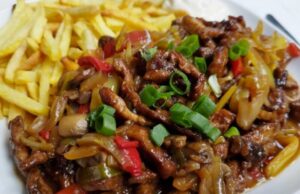 Schweinefleischstreifen aus einer Pfanne: Saftiges Fleisch mit Gemüse, Champignons und knusprigen Pommes Rezept für asiatische Schweinepfanne mit Gemüse und Pommes