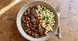 Schweinefleisch mit Champignons und Paprika in Sauce: Einfaches Familienessen mit Nudeln Schweinefleisch mit Champignons und Paprika in Sauce serviert mit Nudeln