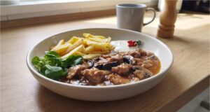 Schweinenacken mit Champignons: Saftiges Fleisch in reichhaltiger Sauce mit knusprigen Pommes Schweinenacken mit Champignons und Pommes auf einem Teller