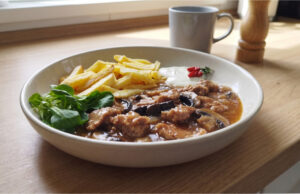 Schweinenacken mit Champignons: Saftiges Fleisch in reichhaltiger Sauce mit knusprigen Pommes Schweinenacken mit Champignons und Pommes auf einem Teller