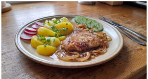 Schweineschnitzel mit Zwiebelsoße: Saftiges Fleisch dank langer Marinade Schweineschnitzel mit Zwiebelsoße und Kartoffeln auf einem Teller