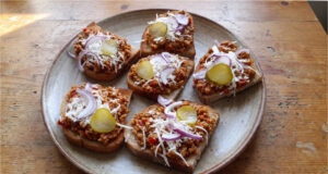 Teuflische Fleischmischung für Brotscheiben: Pikantes Fleisch mit Tomaten, Paprika und Knoblauch Teuflische Fleischmischung auf geröstetem Brot serviert