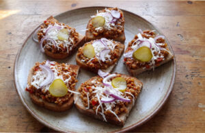 Teuflische Fleischmischung für Brotscheiben: Pikantes Fleisch mit Tomaten, Paprika und Knoblauch Teuflische Fleischmischung auf geröstetem Brot serviert