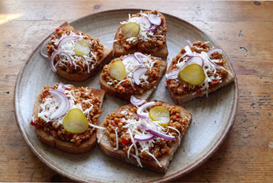 Teuflische Fleischmischung für Brotscheiben: Pikantes Fleisch mit Tomaten, Paprika und Knoblauch Teuflische Fleischmischung auf geröstetem Brot serviert