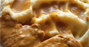 Hähnchenbrust mit pikanter Sauce und Kartoffelpüree: Einfaches Mittagessen mit Tomatensalat Hähnchenbrust mit pikanter Sauce, Kartoffelpüree und Tomatensalat auf einem Teller