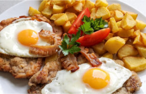 Holsteiner Schweineschnitzel: Saftiges Fleisch mit Spiegelei, Speck und knusprigen Kartoffeln Holsteiner Schweineschnitzel mit Spiegelei und Speck auf Kartoffeln serviert