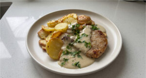 Schnelle Schweinekoteletts mit Parmesan-Sahnesoße: Saftiges Fleisch dank Nachgaren unter Alufolie Saftige Schweinekoteletts mit Parmesan-Sahnesoße auf einem Teller serviert