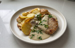Schnelle Schweinekoteletts mit Parmesan-Sahnesoße: Saftiges Fleisch dank Nachgaren unter Alufolie Saftige Schweinekoteletts mit Parmesan-Sahnesoße auf einem Teller serviert